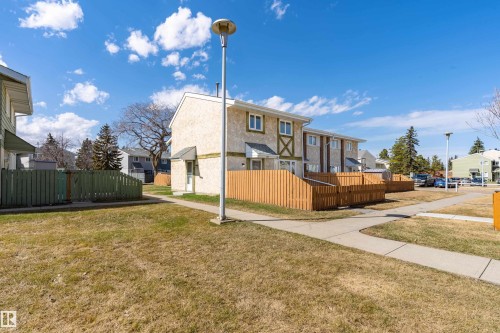 Townhome exteriors featuring light stucco siding and a brown privacy fence - 15C Callingwood Crest, Edmonton, AB - Outdoor