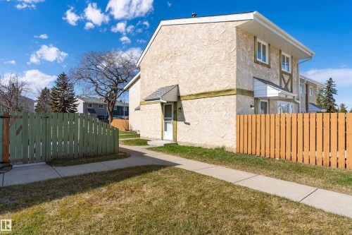 Cream stucco exterior with white trim and a green wood fence - 15C Callingwood Crest, Edmonton, AB - Outdoor