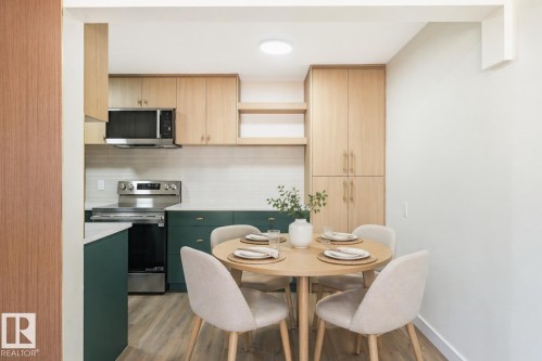 Kitchen featuring light wood-finish upper cabinetry, dark green lower cabinetry, and stainless steel appliances - 15C Callingwood Crest, Edmonton, AB - Indoor Photo Showing Dining Room