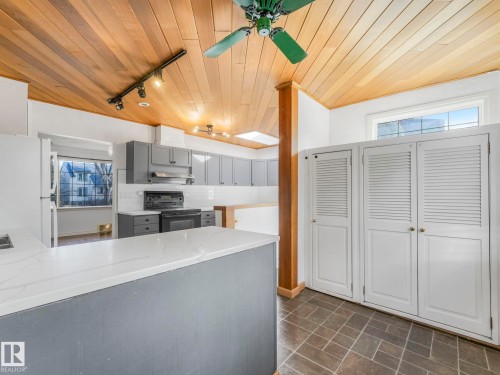 Kitchen featuring wood-panel ceiling, track lighting, gray cabinetry, white subway tile backsplash, and a breakfast bar with a solid surface countertop - 11643 76 Avenue, Edmonton, AB - Indoor Photo Showing Kitchen