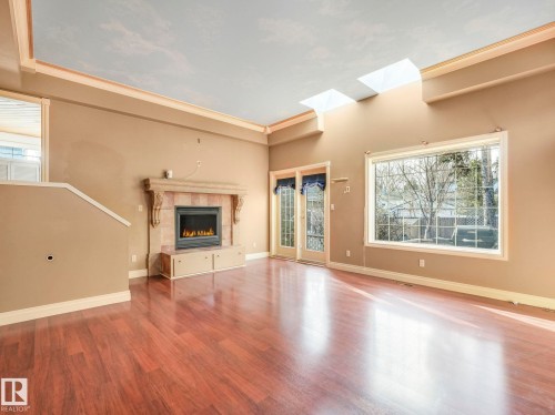 Spacious living area featuring high ceilings, two skylights, and wood-finish flooring - 11643 76 Avenue, Edmonton, AB - Indoor With Fireplace