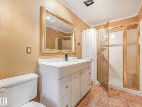 Bathroom featuring a white vanity with integrated sink, gold-framed mirror, and a standing shower with gold-framed glass enclosure - 11643 76 Avenue, Edmonton, AB - Indoor Photo Showing Bathroom