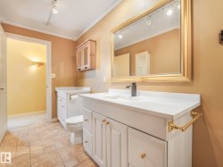 Bathroom featuring a white vanity with gold-tone hardware, a rectangular undermount sink, a matte black faucet, and a large gold-framed mirror - 