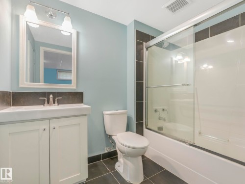 Bathroom featuring a white vanity with integrated sink, framed mirror, and two-light fixture - 11643 76 Avenue, Edmonton, AB - Indoor Photo Showing Bathroom