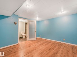 Spacious room featuring wood-finish flooring, light blue walls, and a drop ceiling with recessed lighting - 