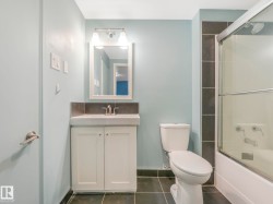 Bathroom featuring a single vanity with storage, a rectangular mirror, and a combination shower/bathtub with a sliding glass enclosure - 