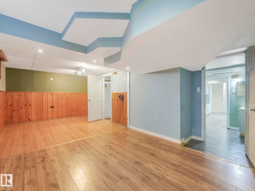 Spacious room featuring wood-finish flooring and a partial wood panel accent wall - 11643 76 Avenue, Edmonton, AB - Indoor Photo Showing Other Room