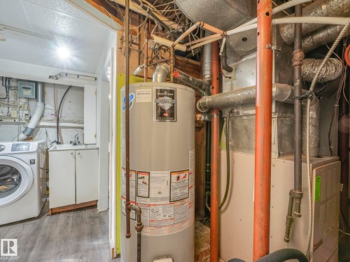 Utility room featuring a water heater, furnace, and a laundry area with a sink and cabinetry - 11643 76 Avenue, Edmonton, AB - Indoor Photo Showing Laundry Room