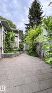 Paver walkway bordered by a stone retaining wall and mature landscaping - 