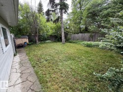 Expansive green space featuring mature trees and a flagstone pathway - 