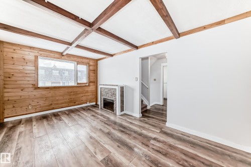 Living space featuring wood-finish flooring and a wood-paneled accent wall - 3325 107 Avenue Nw, Edmonton, AB - Indoor Photo Showing Other Room