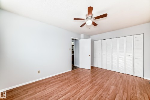 Spacious interior featuring wood-finish flooring, light grey walls, and a ceiling fan with wood-tone blades - 3325 107 Avenue Nw, Edmonton, AB - Indoor Photo Showing Other Room