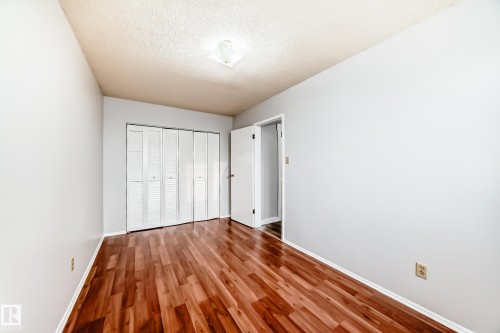 Interior room featuring wood-finish flooring, light grey painted walls, and a white bi-fold closet door - 3325 107 Avenue Nw, Edmonton, AB - Indoor Photo Showing Other Room