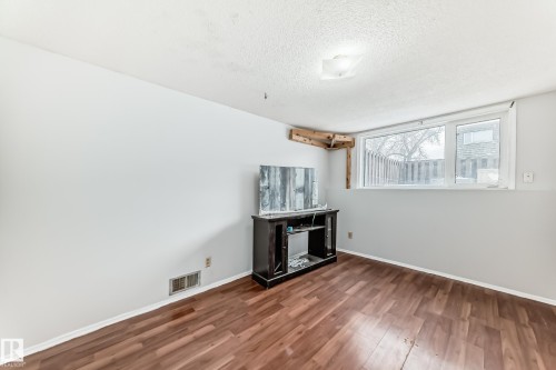 Room featuring wood-finish flooring, white painted walls, and a large window - 3325 107 Avenue Nw, Edmonton, AB - Indoor Photo Showing Other Room