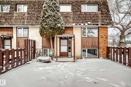 Multi-level townhome exterior featuring an entrance canopy, wood-shingle roof, and a fenced front yard - 3325 107 Avenue Nw, Edmonton, AB - Outdoor