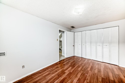 Room featuring wood-finish flooring, white walls, and a multi-panel louvered closet - 3325 107 Avenue Nw, Edmonton, AB - Indoor Photo Showing Other Room