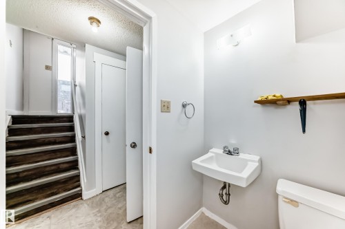 Compact bathroom featuring a wall-mounted sink with chrome faucet, a white toilet, and a towel ring - 3325 107 Avenue Nw, Edmonton, AB - Indoor