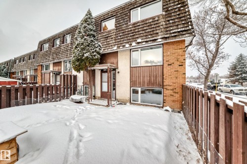 Exterior townhome with a wood shingle roof, brick facade accents, and a fenced yard - 3325 107 Avenue Nw, Edmonton, AB - Outdoor