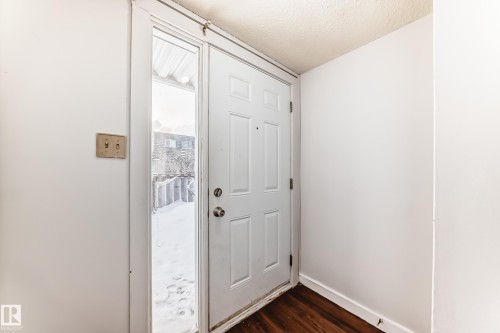 Entryway featuring a paneled door, wood-finish flooring, and white painted walls - 3325 107 Avenue Nw, Edmonton, AB - Indoor Photo Showing Other Room
