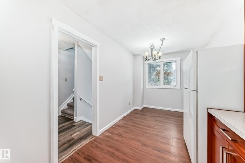 Dining area featuring wood-finish flooring, a multi-light chandelier, a window with natural light, and a built-in countertop with wood cabinetry - 3325 107 Avenue Nw, Edmonton, AB - Indoor Photo Showing Other Room