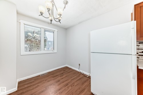 Dining area featuring wood-finish flooring, a white window frame with a multi-pane window, and a decorative chandelier - 3325 107 Avenue Nw, Edmonton, AB - Indoor Photo Showing Other Room