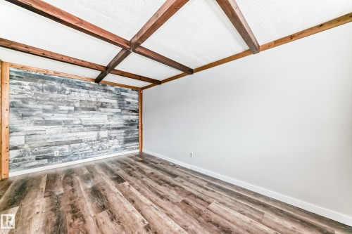 Interior space featuring exposed wood beams, wood-finish flooring, and a distressed wood accent wall - 3325 107 Avenue Nw, Edmonton, AB - Indoor Photo Showing Other Room
