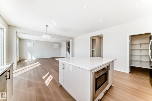 The property features a kitchen island with a built-in microwave, white countertops, and light-colored cabinetry - 1516 206 Street Nw, Edmonton, AB - Indoor Photo Showing Kitchen