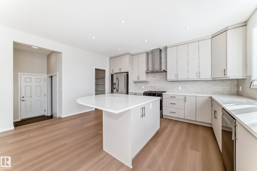 The kitchen features light-toned cabinetry, light countertops, and stainless steel appliances - 1516 206 Street Nw, Edmonton, AB - Indoor Photo Showing Kitchen With Upgraded Kitchen