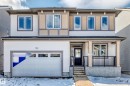 The property features a two-story exterior with light-colored siding, a front entry with a dark door, and a covered porch with dark railings - 1516 206 Street Nw, Edmonton, AB  - Outdoor 