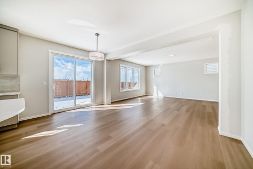 Spacious open concept living area featuring light wood flooring, recessed lighting, and large windows, including a sliding glass door - 1516 206 Street Nw, Edmonton, AB - Indoor