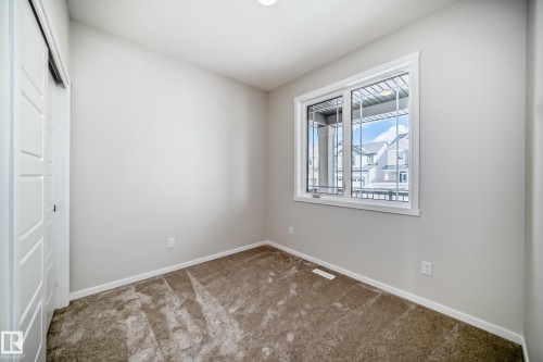 This room features neutral-toned walls, brown carpet, and a window with white trim - 1516 206 Street Nw, Edmonton, AB - Indoor Photo Showing Other Room