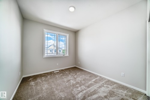 This room features neutral-toned walls, a window providing natural light, and plush carpeting - 1516 206 Street Nw, Edmonton, AB - Indoor Photo Showing Other Room