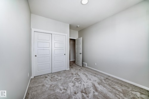 Bedroom featuring light gray walls, gray carpet, white trim, and a white sliding closet door - 1516 206 Street Nw, Edmonton, AB - Indoor Photo Showing Other Room
