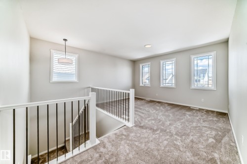 This expansive space features light gray carpeting, neutral wall paint, and multiple windows providing natural light - 1516 206 Street Nw, Edmonton, AB - Indoor Photo Showing Other Room