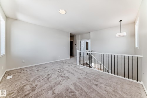 The property features a spacious room with carpet flooring, light-colored walls, and large windows providing natural light - 1516 206 Street Nw, Edmonton, AB - Indoor Photo Showing Other Room