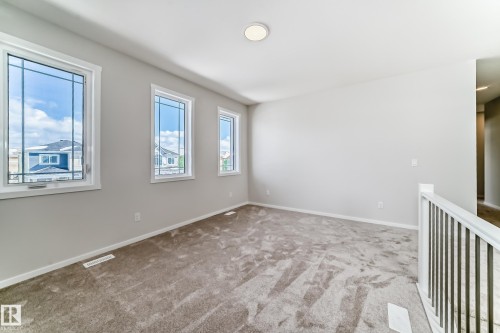 Inviting room with light neutral walls, gray carpet, and three windows providing natural light - 1516 206 Street Nw, Edmonton, AB - Indoor Photo Showing Other Room