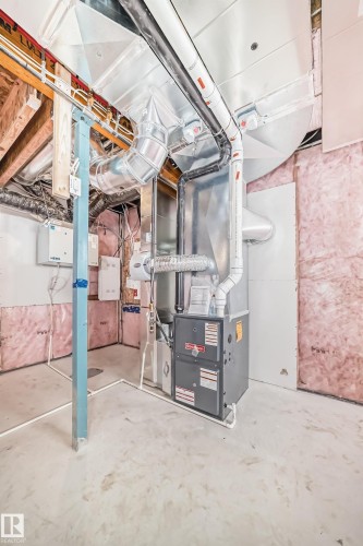 The property features a utility room with a furnace unit, exposed ceiling ductwork, and partially insulated walls - 1516 206 Street Nw, Edmonton, AB - Indoor Photo Showing Basement