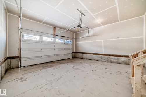 The garage features a concrete floor, a white overhead door with windows, and an automatic garage door opener - 1516 206 Street Nw, Edmonton, AB - Indoor Photo Showing Garage