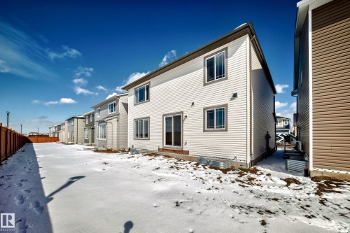 The property features white horizontal siding and a sliding glass door leading to the yard - 1516 206 Street Nw, Edmonton, AB - Outdoor With Exterior