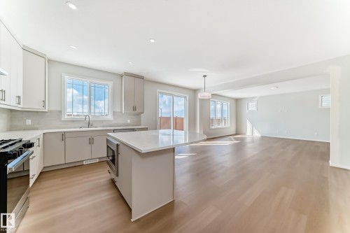 The property features an open concept kitchen and living area, complete with a kitchen island, recessed lighting, and hardwood flooring - 1516 206 Street Nw, Edmonton, AB - Indoor Photo Showing Kitchen With Upgraded Kitchen