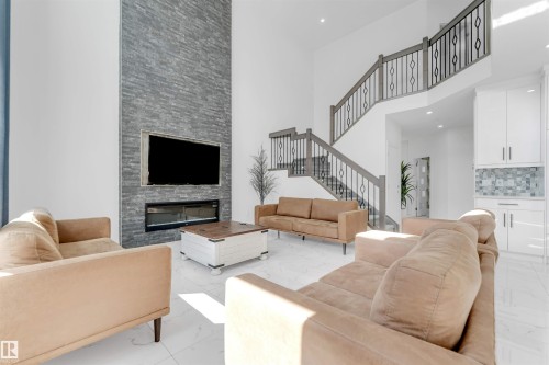 Two-story living area with high ceilings, featuring a floor-to-ceiling stacked stone fireplace with an integrated media center and linear electric fireplace - 1923 19 Avenue, Edmonton, AB - Indoor Photo Showing Living Room With Fireplace
