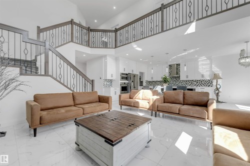 Two-story living area featuring a grand staircase with wrought iron balusters and a wood handrail - 1923 19 Avenue, Edmonton, AB - Indoor Photo Showing Living Room