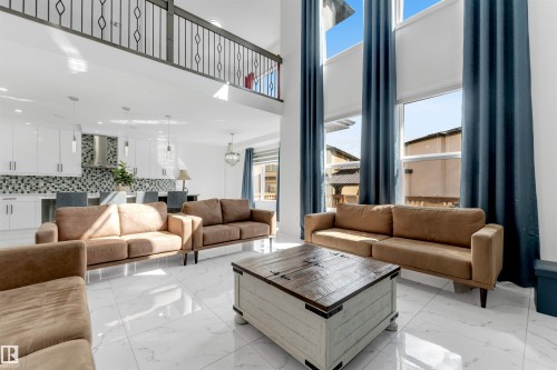 Two-story living area with high ceilings, large windows featuring tall drapery, and polished tile flooring - 1923 19 Avenue, Edmonton, AB - Indoor Photo Showing Living Room