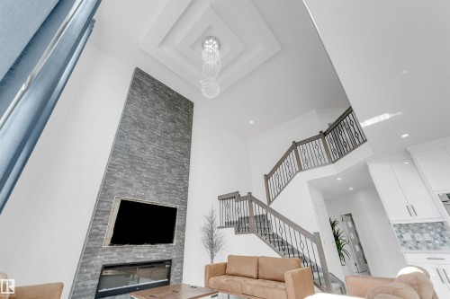 Vaulted ceiling with tiered tray detailing and a chandelier - 1923 19 Avenue, Edmonton, AB - Indoor Photo Showing Other Room With Fireplace