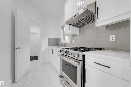 Sleek kitchen featuring white cabinetry, a stainless steel range with matching range hood, and a gray subway tile backsplash - 1923 19 Avenue, Edmonton, AB - Indoor Photo Showing Kitchen With Upgraded Kitchen