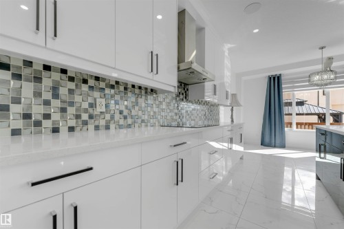 Gleaming kitchen featuring white high-gloss cabinetry, a mosaic tile backsplash, and polished flooring - 1923 19 Avenue, Edmonton, AB - Indoor Photo Showing Kitchen