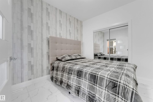 Modern bedroom featuring a paneled accent wall and large mirrored closet doors - 1923 19 Avenue, Edmonton, AB - Indoor Photo Showing Bedroom