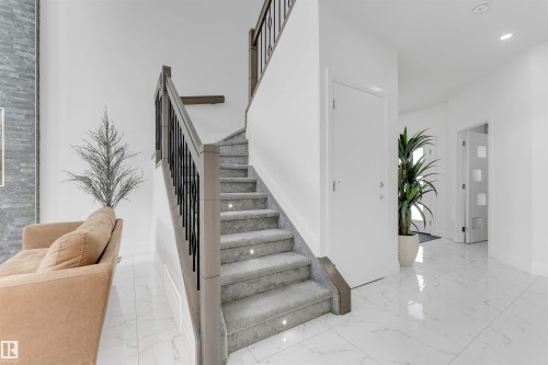 Carpeted staircase with integrated step lighting and dark wood-finish handrail with black balusters - 1923 19 Avenue, Edmonton, AB - Indoor Photo Showing Other Room