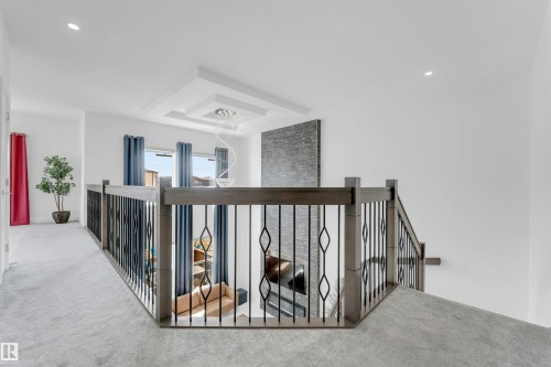 Upper-level landing featuring light gray carpeting and a wood-finish railing with decorative metal spindles - 1923 19 Avenue, Edmonton, AB - Indoor Photo Showing Other Room