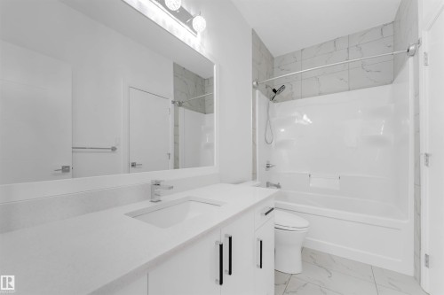Contemporary bathroom featuring a white vanity with integrated sink, chrome faucet, and expansive mirror with overhead lighting - 1923 19 Avenue, Edmonton, AB - Indoor Photo Showing Bathroom